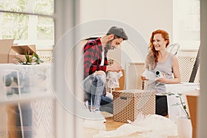 Smiling woman and man packing stuff while moving out from home