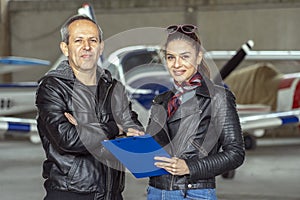 Smiling Woman and Man Pilots in a Hangar