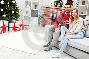 Smiling woman and man sit embraced on gray couch