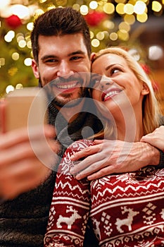 Smiling woman and man in warm sweaters taking selfie picture wit