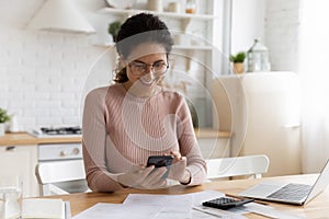 Smiling woman manage budget paying on cellphone online