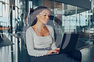 Smiling woman manager working on laptop while sitting in modern office during working day