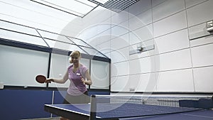 Smiling woman masterfully playing the tennis on court in slowmotion