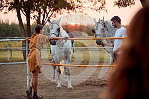 Smiling woman and men on the ranch at sunset with their horse