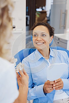 Smiling woman with mirror talking with dentist