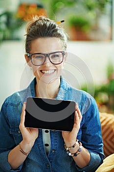 Smiling woman in modern house in sunny day showing tablet PC