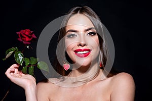 Smiling woman with naked shoulder red lips and rose flower. Fashion beauty portrait on studio black background.