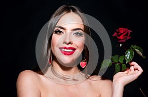 Smiling woman with naked shoulder red lips and rose flower. Fashion beauty portrait on studio black background.