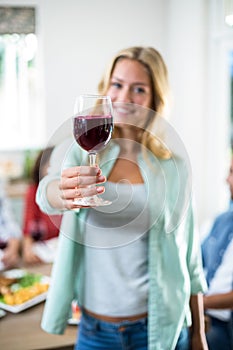 Smiling woman offering red wine glass