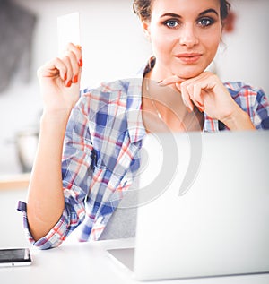 Smiling woman online shopping using computer and credit card in kitchen