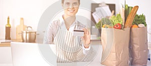 Smiling woman online shopping using computer and credit card in kitchen