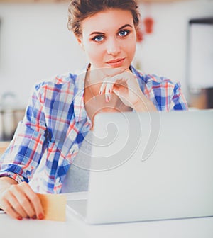 Smiling woman online shopping using computer and credit card in kitchen