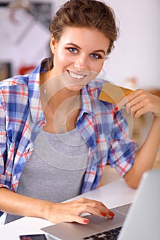 Smiling woman online shopping using computer and credit card in kitchen