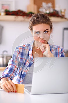 Smiling woman online shopping using computer and credit card in kitchen