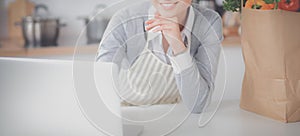 Smiling woman online shopping using computer and credit card in kitchen