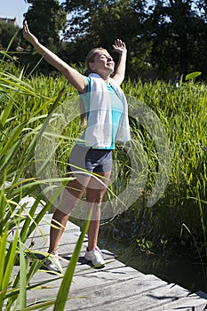 Smiling woman opening her arms wide for mindfulness, sunny outdoors