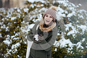 smiling woman outdoors in park in winter throwing snowballs