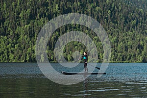Smiling woman paddleboarding on the mountain lake