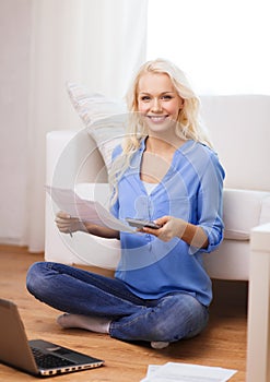 Smiling woman with papers, laptop and calculator
