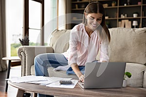 Smiling woman pay bills, manage finances use laptop at home