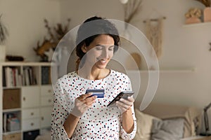 Smiling woman paying online by credit card, using smartphone