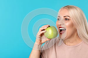 Smiling woman with perfect teeth and apple on color background. Space for text