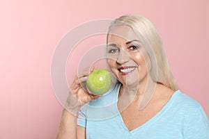 Smiling woman with perfect teeth and apple on color background, space for text