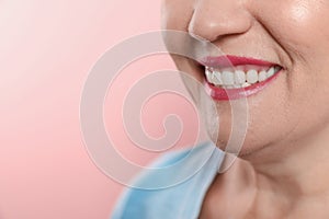 Smiling woman with perfect teeth on color background, closeup.