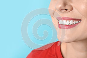 Smiling woman with perfect teeth on color background, closeup.