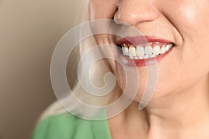 Smiling woman with perfect teeth on color background, closeup.