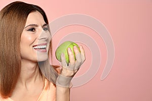 Smiling woman with perfect teeth and green apple on color background.