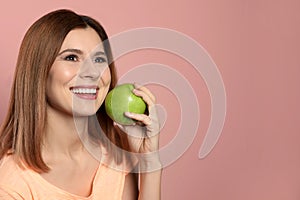 Smiling woman with perfect teeth and green apple on color background.