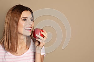 Smiling woman with perfect teeth and red apple on color background.