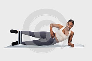 Smiling Woman Performing Side Plank Exercise With Resistance Band