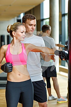 Smiling woman with personal trainer boxing in gym