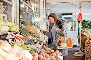 Smiling woman buying various vegetables