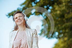 smiling woman in pink dress and white jacket in city