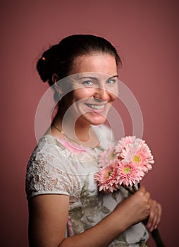 smiling woman with pink flowers. Studio pink background