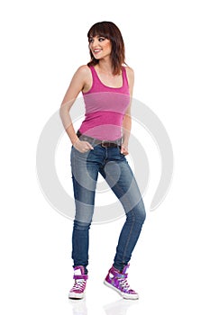 Smiling Woman In Pink Tanktop, Jeans And Sneakers Looking Away Over The Shoulder