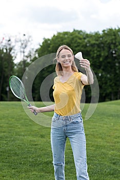 Smiling woman playing badminton game in park, summertime concept