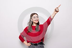 Smiling woman pointing up and looking at the camera over gray background