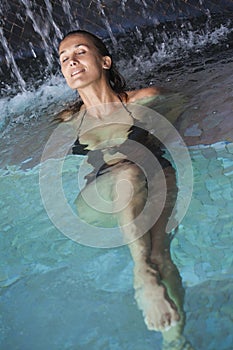 Smiling Woman in a pool under waterfalls
