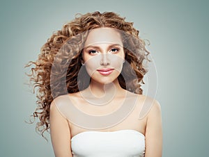 Smiling woman portrait. Redhead girl with long healthy wavy hairstyle on gray background