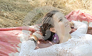 Smiling woman portrait rest outdoor lie on an indian tapestry in park