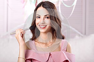 Smiling woman powdering her face with brush