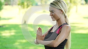 Smiling woman practising yoga exercise in summer park. Fitness a lifestyle