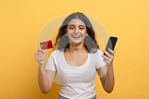 Cheerful woman holding phone and credit card photo