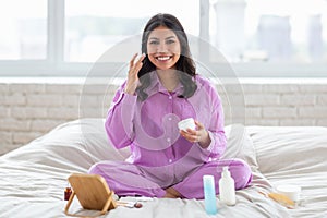 Smiling woman in purple pajamas on bed