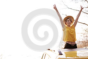 Smiling Woman with Raised Arms at Car Sunroof