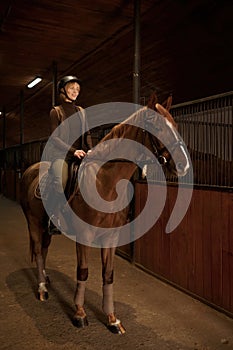 Smiling woman rancher riding out stable on horse